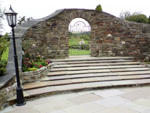 Gated garden archway with ornate metal gate leading to gardens. Design and build by Evergreen Wales landscapers.