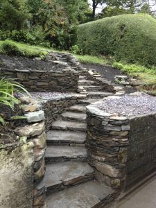 Curved natural stone steps with stonework decorated leading to gardens. Designed and built by Evergreen Wales.