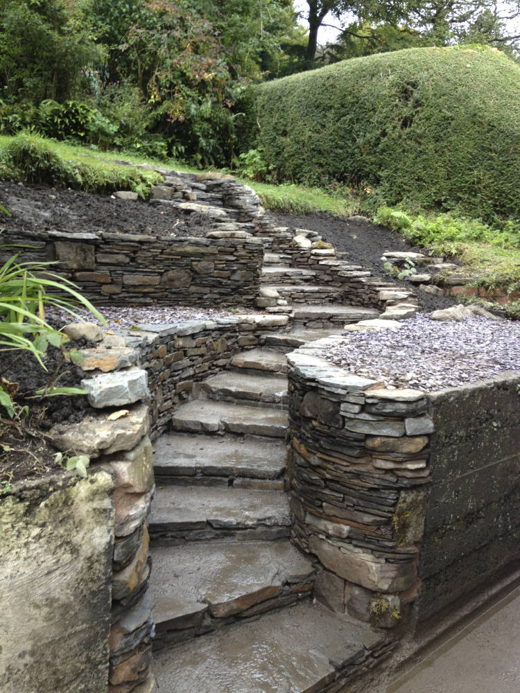 Curved natural stone steps with stonework decorated leading to gardens