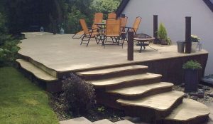 Curved timber decking with steps and seating area designed and built by Evergreen Wales