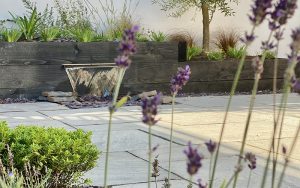 Hard Landscaping design of a water feature pouring water into stones. Beautifully landscaped patio.