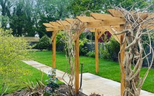 Timber trellis for planting climbing flowers such as wisteria in a landscaped garden, designed and built by Evergreen Wales