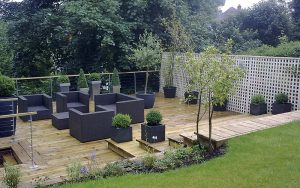 Raised decking with steps down to outdoor seating area and garden planters. Designed and built by Evergreen Wales.