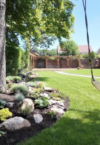 Swing with bespoke rockery planting a pergola play area in the background